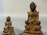 two statues of buddhas sitting on top of a white surface