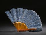 un éventail bleu et or posé sur une surface noire