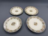 quatre assiettes ornées de motifs dorés et blancs, posées sur une table