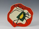 une assiette rouge et blanche sur laquelle est représentée une araignée noire et jaune