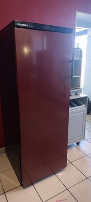 un réfrigérateur rouge dans une cuisine au sol carrelé