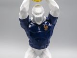 figurine représentant un homme tenant un ballon de football au-dessus de sa tête