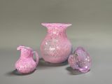 a pink glass vase and two small vases on the table