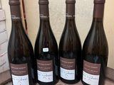 four bottles of wine are lined up on a wooden table