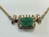 a close up of a necklace with a green stone surrounded by diamonds