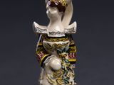 une image représentant une figurine de femme portant un chapeau et une robe