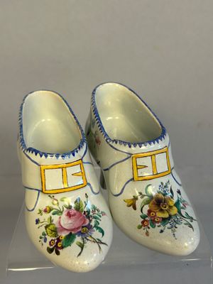 a pair of clogs with flowers on them on a clear surface
