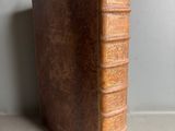 an old brown book sitting on top of a table next to a wall