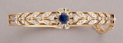 a close up of a gold bracelet with a sapphire and diamonds