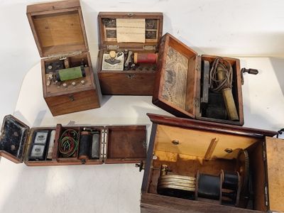 quatre boîtes en bois contenant divers objets, posées sur une surface blanche