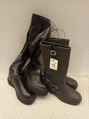une paire de bottes en cuir noir à semelles en caoutchouc posées sur une surface blanche