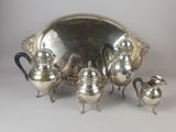 a silver tea set on a table with a mirror in the background