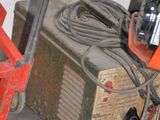 a small machine that is sitting on the floor next to a red cart