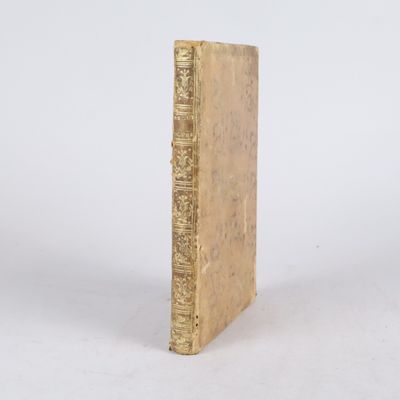 un vieux livre posé sur une table à côté d'un mur blanc