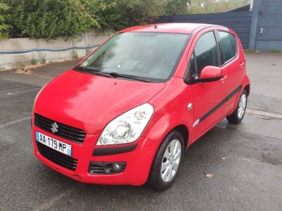La petite voiture rouge est garée sur le parking.