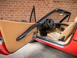 a red sports car with a tan interior parked in front of a brick wall