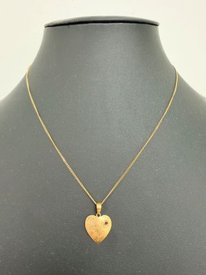 un pendentif en forme de cœur en or sur le torse d'un mannequin