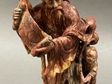 an old figurine of a man holding a bird on a stand