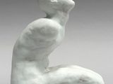 a white sculpture of a man sitting on his knees