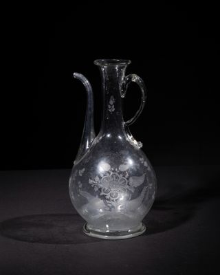 an old glass vase with a handle on a black surface