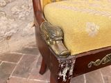 a chair with a yellow cushion on it in front of a stone wall