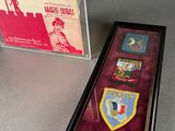 a display case with three different badges and a book on a table