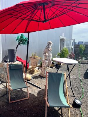deux chaises de jardin et une table avec un parasol rouge