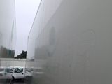 a white truck driving down a narrow street in the rain