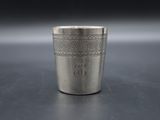 a close up of a silver shot glass on a table
