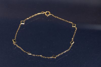 un bracelet en chaîne dorée à maillons carrés sur un fond noir