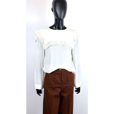 un chemisier blanc à volants et un pantalon marron sur une tête de mannequin
