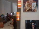 two pictures of a woman on the wall and a lamp on the floor