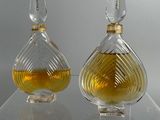 two bottles of perfume sitting on a clear shelf