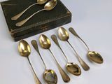 six cuillères et une boîte de couverts sont posés sur une table