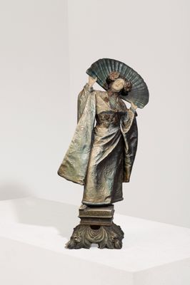 statue d'une femme tenant un éventail, posée sur un socle dans une pièce