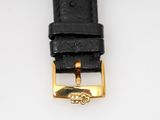 a close up of a black leather watch strap with a gold buckle