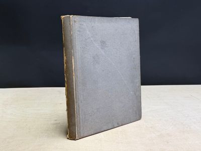 un vieux livre posé sur une table en bois, près d'un mur noir