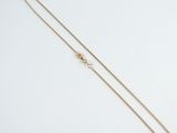 a gold chain necklace with a heart charm on a white background
