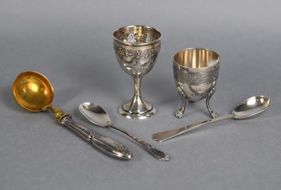 three silver plated goblets, spoons and spoon rest on a gray surface