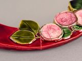 a picture of a red plate with three pink flowers on it