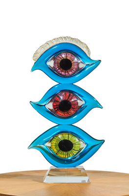 a sculpture of three different colored eyes on top of a wooden table