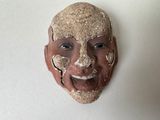 un masque en argile accroché au mur d'une pièce