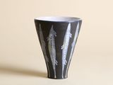 une tasse en noir et blanc sur laquelle sont peintes des plumes