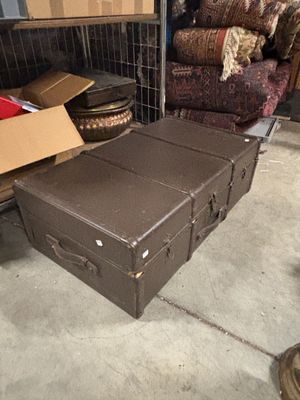 une valise marron posée par terre à côté d'une pile de cartons