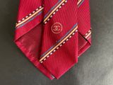a close up of a red tie with a chanel logo