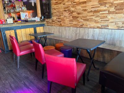 brightly colored chairs and tables in a restaurant with a bar in the background