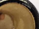 a close up of a black and gold vase on a white table