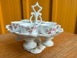 six tasses et soucoupes posées sur un présentoir posé sur une table
