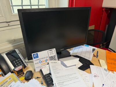 a computer monitor sitting on a desk covered in papers