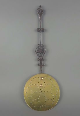 une assiette en or suspendue à un crochet métallique fixé au mur